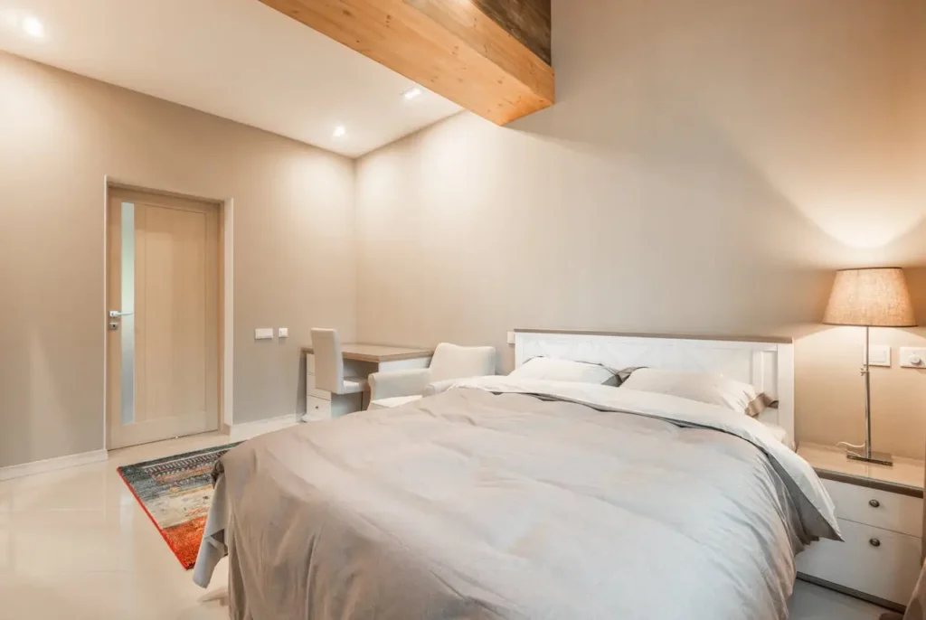 A bedroom scene with an uncluttered bedside table featuring a cordless, portable table lamp