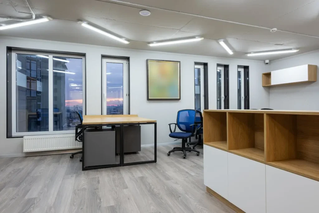 A floor-to-ceiling wooden slatted screen illuminated by recessed floor lighting