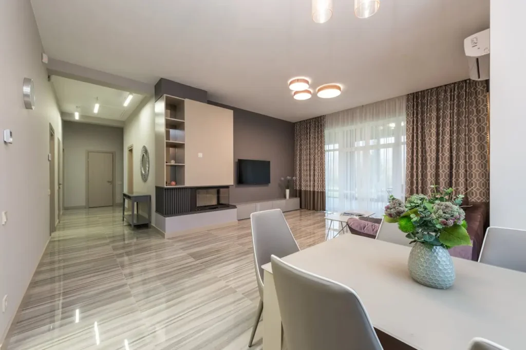 Clean, wide-angle shot of a living room with recessed ceiling lights and soft, indirect light from a hidden cove
